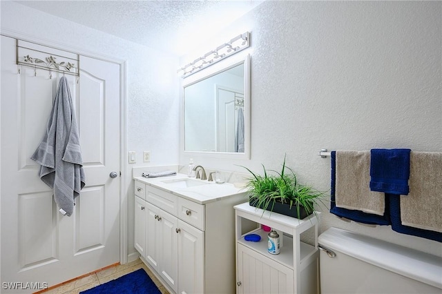 bathroom featuring toilet, a textured ceiling, tile patterned flooring, vanity, and a textured wall