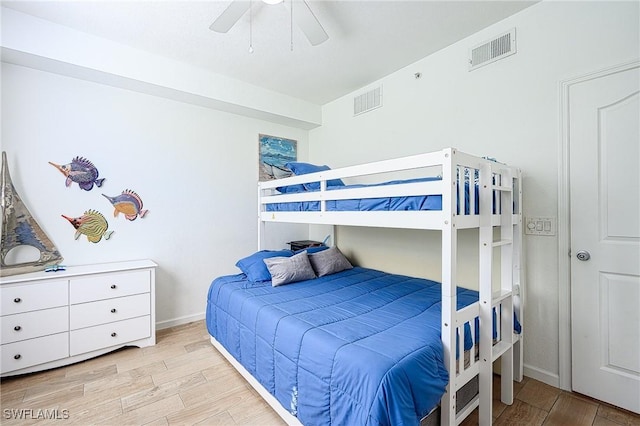 bedroom with light wood finished floors, visible vents, and a ceiling fan