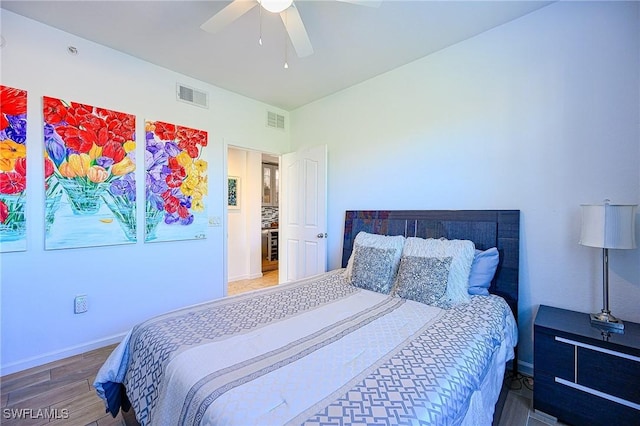 bedroom featuring baseboards, wood finished floors, visible vents, and ceiling fan