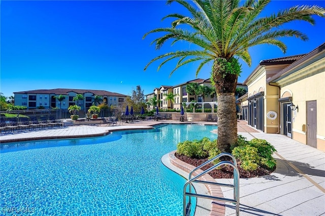 community pool featuring a residential view, a patio, and fence