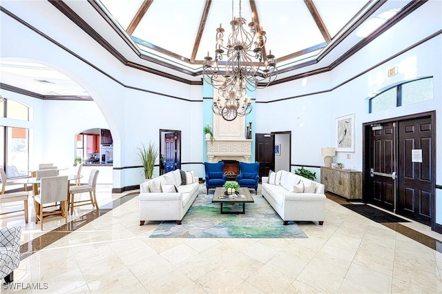 living room featuring baseboards, a high ceiling, arched walkways, ornamental molding, and a chandelier