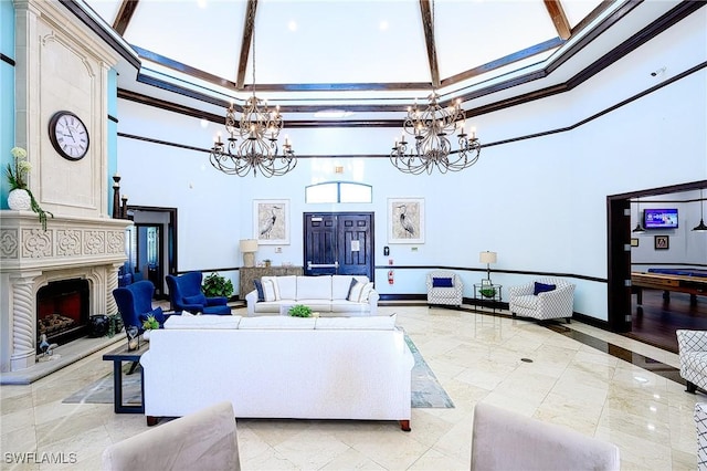 living room with a notable chandelier, a fireplace, a towering ceiling, and ornamental molding