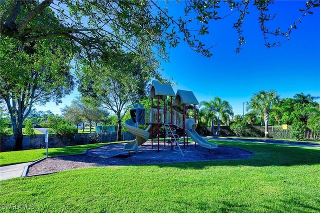 communal playground featuring a yard and fence