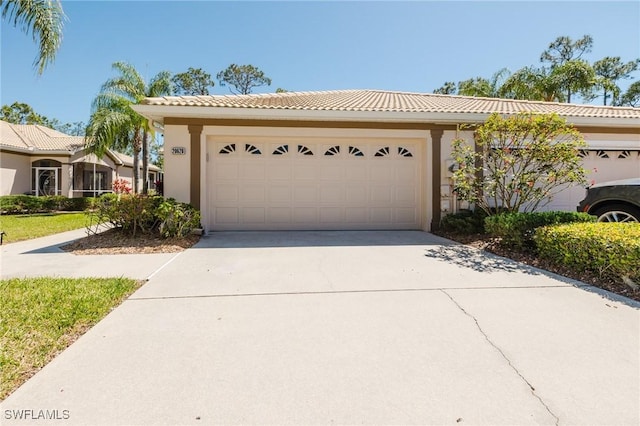 view of front of home with a garage, concrete driveway, stucco siding, and a tiled roof