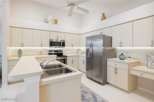 kitchen featuring ceiling fan, light countertops, a towering ceiling, stainless steel appliances, and a sink