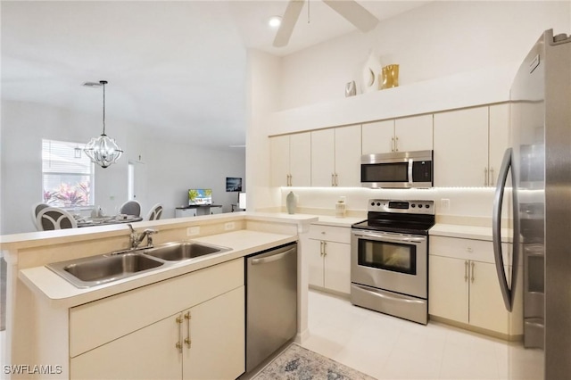 kitchen with decorative light fixtures, light countertops, appliances with stainless steel finishes, a peninsula, and a sink