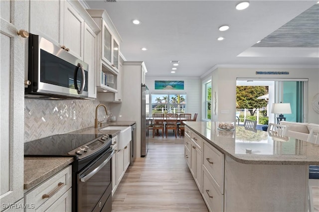 kitchen featuring a healthy amount of sunlight, appliances with stainless steel finishes, a center island, and crown molding