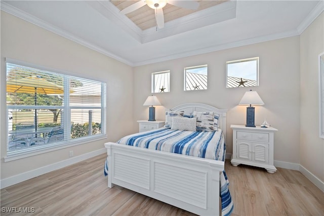 bedroom featuring baseboards, a tray ceiling, light wood-style flooring, ceiling fan, and ornamental molding