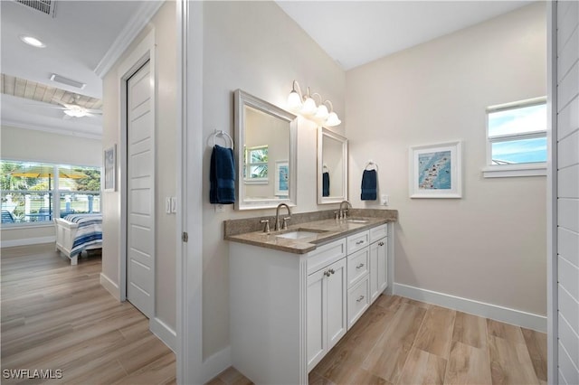 ensuite bathroom featuring wood finished floors, baseboards, visible vents, a sink, and connected bathroom