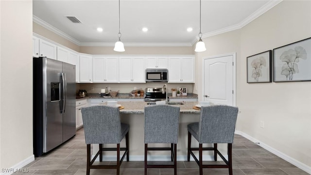 kitchen featuring visible vents, ornamental molding, stainless steel appliances, white cabinetry, and a kitchen bar