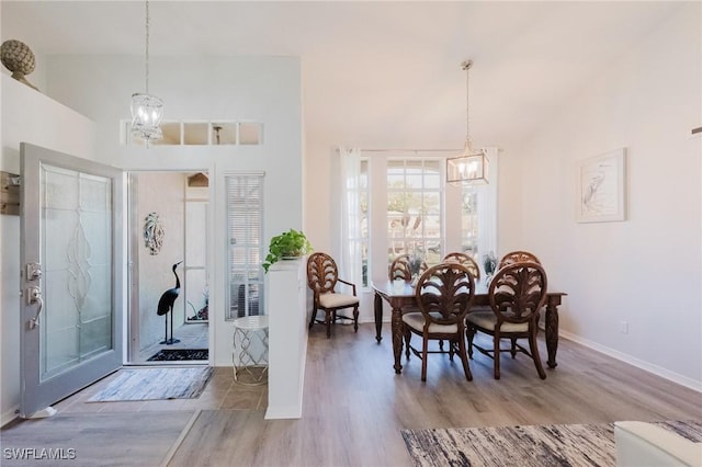 foyer with vaulted ceiling, a notable chandelier, wood finished floors, and baseboards