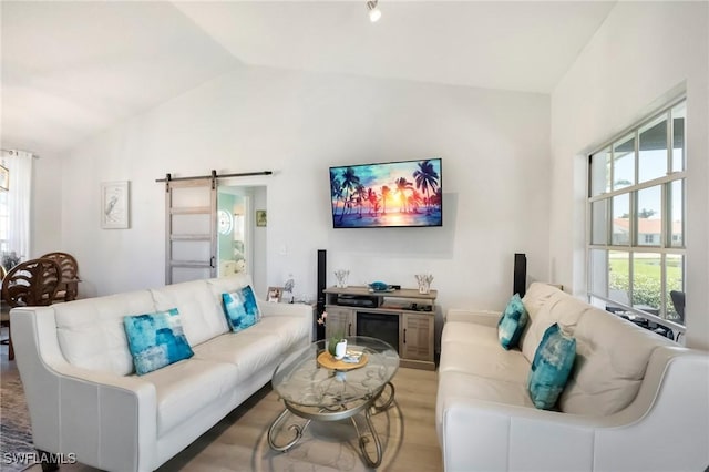 living area featuring a barn door, plenty of natural light, and vaulted ceiling