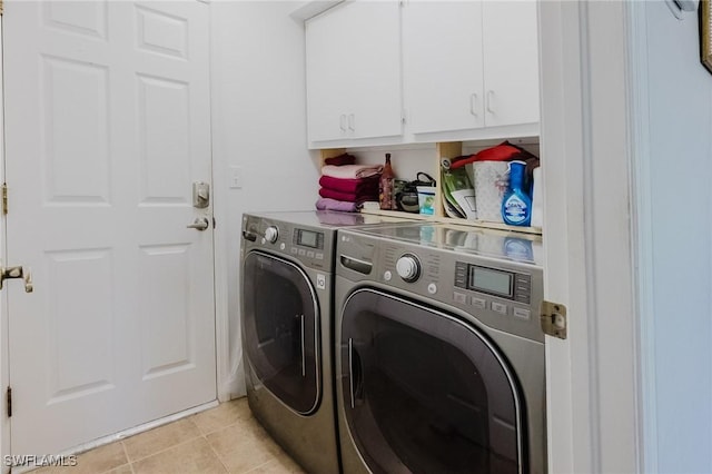 clothes washing area featuring washer and dryer, cabinet space, and light tile patterned floors