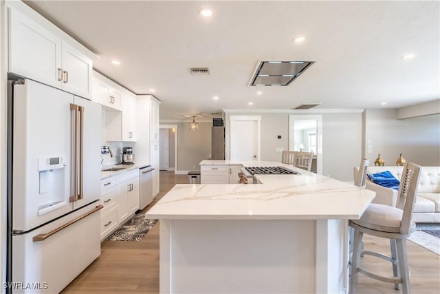 kitchen with a large island, visible vents, white cabinets, and white appliances