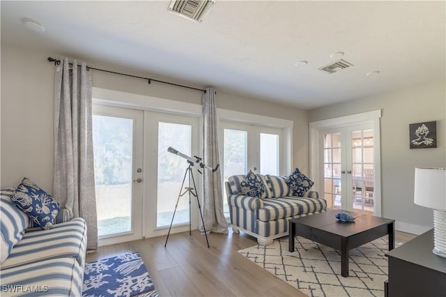 living area with visible vents, light wood-style flooring, french doors, and baseboards