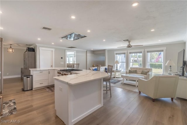 kitchen with visible vents, light wood-style floors, crown molding, and white cabinetry