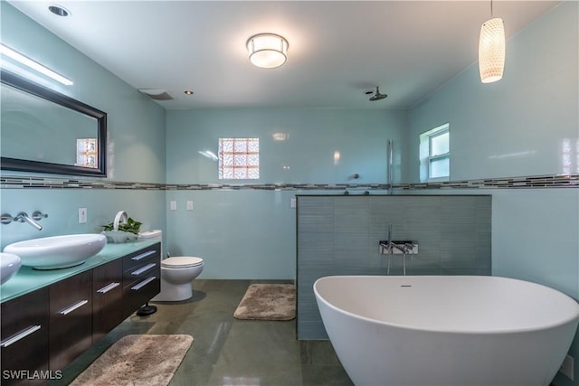 bathroom with a freestanding tub, toilet, a sink, tile walls, and double vanity