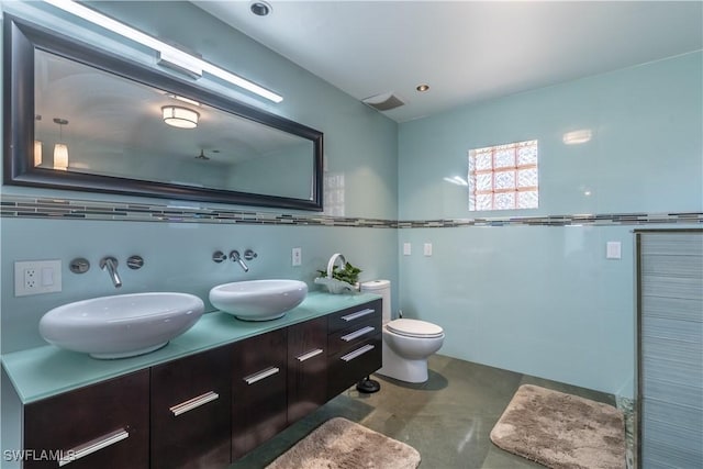 full bath featuring double vanity, visible vents, toilet, and a sink