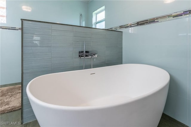 full bathroom with a freestanding bath and tile walls