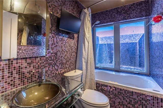 bathroom with a sink, tiled tub, tile walls, and toilet