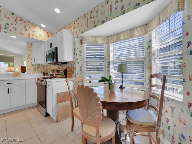 kitchen featuring electric stove, stainless steel microwave, light tile patterned flooring, white cabinets, and wallpapered walls