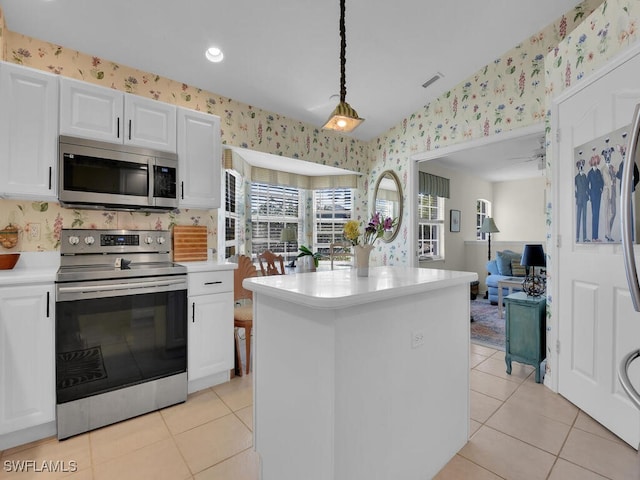 kitchen with appliances with stainless steel finishes, light countertops, and wallpapered walls