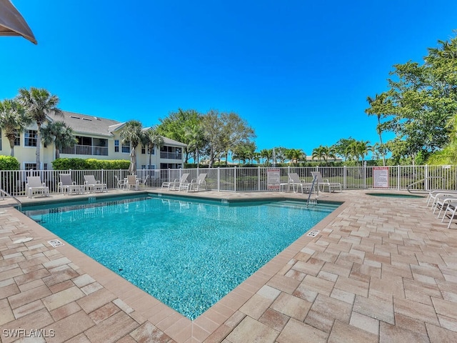 community pool with a patio and fence