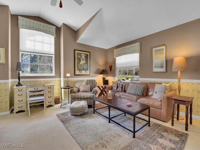 living room featuring a wainscoted wall, plenty of natural light, and vaulted ceiling