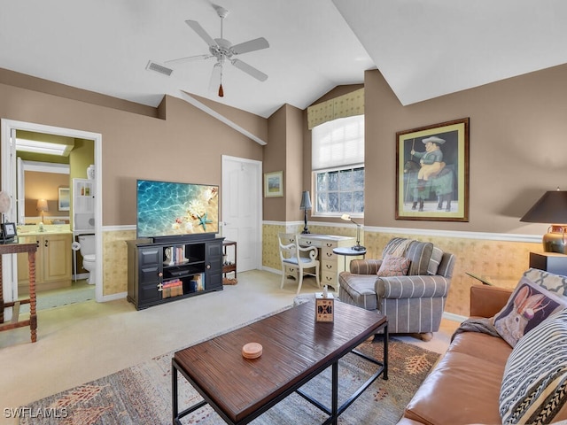 living room featuring visible vents, a ceiling fan, wainscoting, light colored carpet, and vaulted ceiling