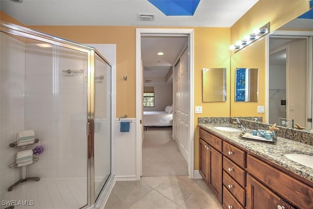 bathroom with visible vents, double vanity, a sink, a shower stall, and connected bathroom