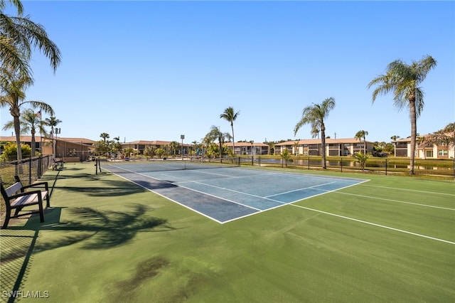 view of tennis court with fence and a residential view