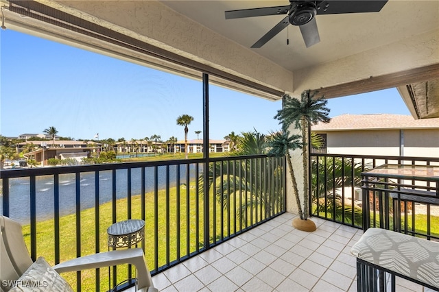 balcony featuring a residential view, ceiling fan, and a water view