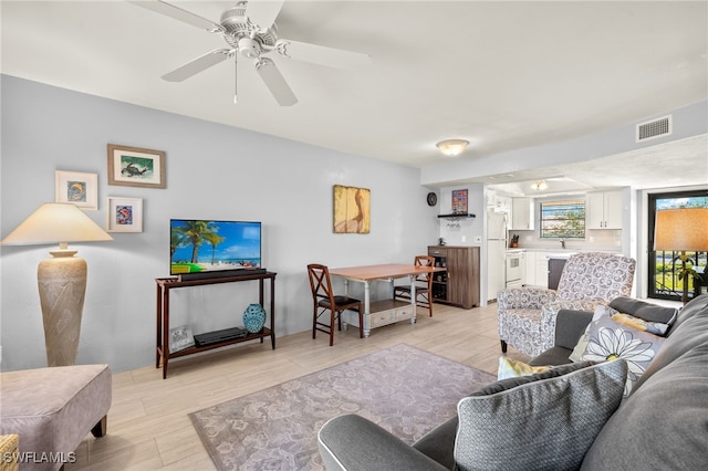 living area featuring light wood finished floors, visible vents, bar, and a ceiling fan