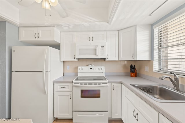 kitchen with a sink, white appliances, light countertops, and white cabinetry