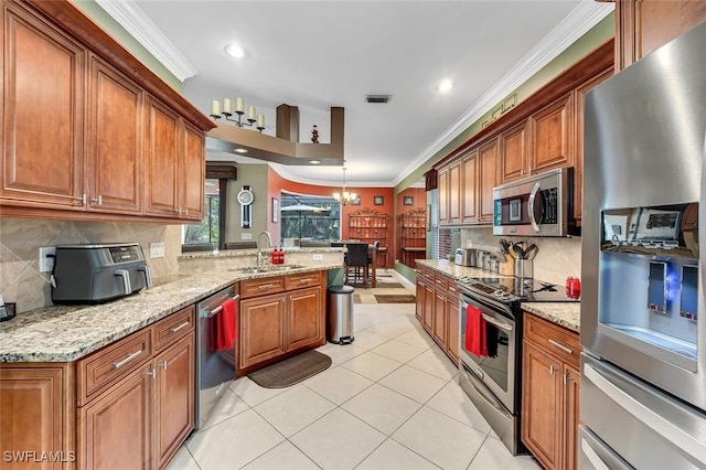 kitchen featuring brown cabinets, ornamental molding, a sink, stainless steel appliances, and a peninsula