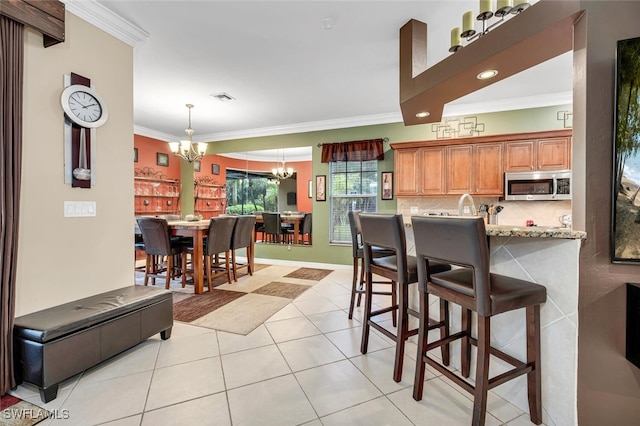 kitchen featuring a notable chandelier, stainless steel microwave, tasteful backsplash, and crown molding