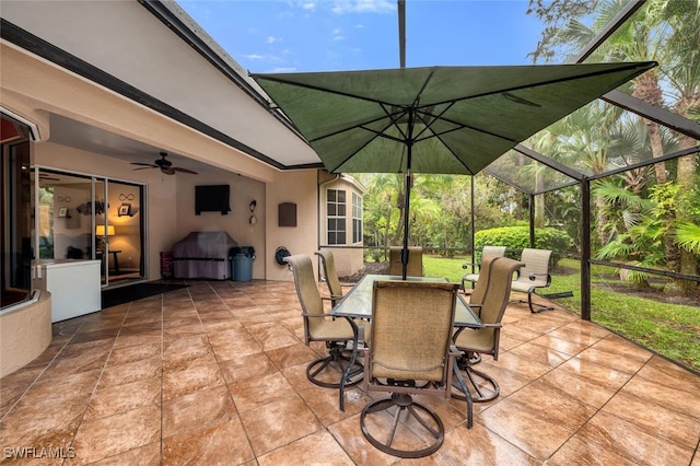 view of patio / terrace featuring area for grilling, glass enclosure, outdoor dining space, and ceiling fan