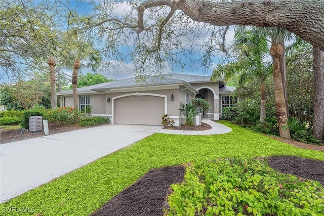 single story home featuring a front lawn, a garage, driveway, and stucco siding