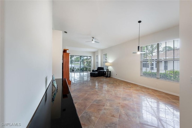 unfurnished living room with a ceiling fan and baseboards