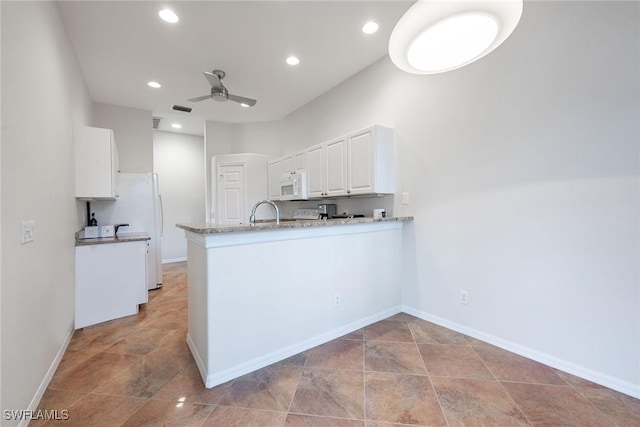 kitchen with white appliances, a ceiling fan, a peninsula, recessed lighting, and white cabinets