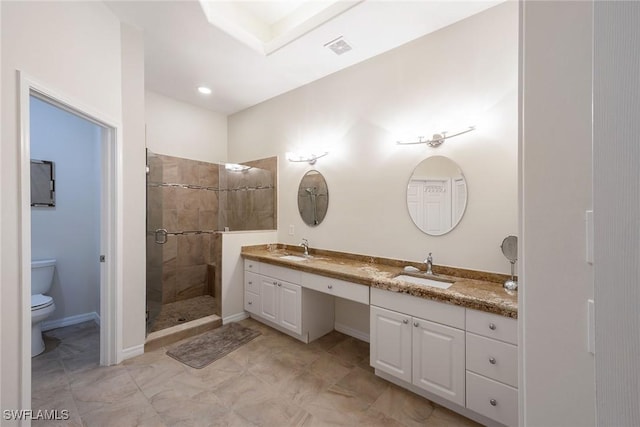 bathroom featuring double vanity, a shower stall, toilet, and a sink