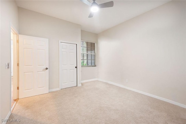 unfurnished bedroom with light carpet, a ceiling fan, and baseboards