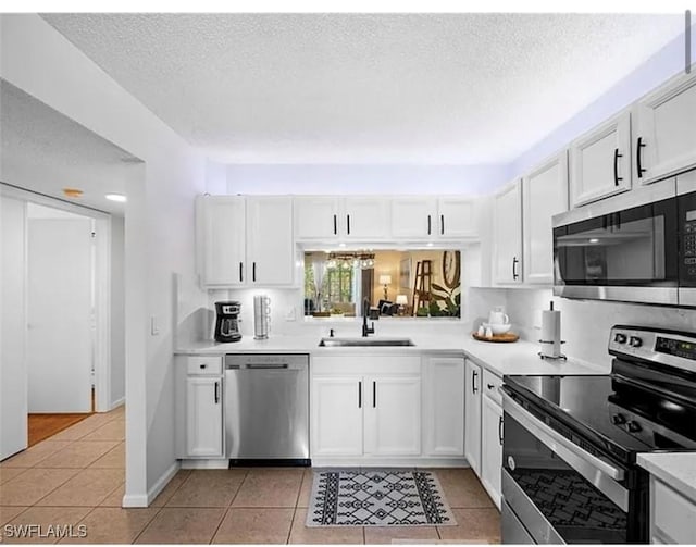 kitchen with a sink, appliances with stainless steel finishes, light countertops, and light tile patterned floors