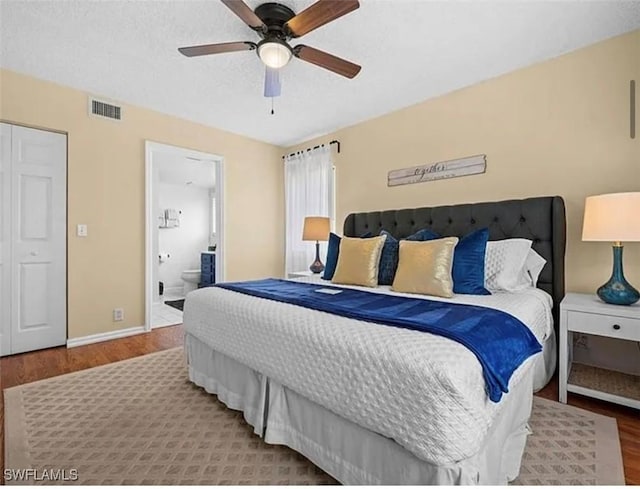 bedroom featuring wood finished floors, visible vents, ceiling fan, a textured ceiling, and connected bathroom