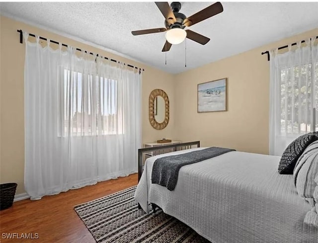 bedroom featuring a textured ceiling, a ceiling fan, and wood finished floors