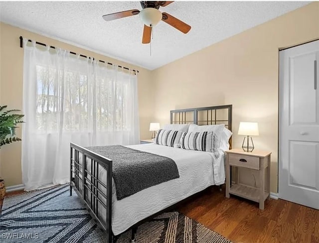 bedroom featuring ceiling fan, wood finished floors, and a textured ceiling