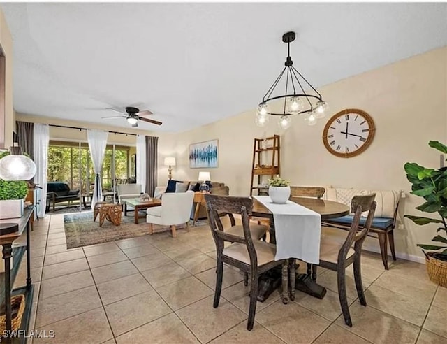 dining space featuring light tile patterned flooring, ceiling fan with notable chandelier, and baseboards