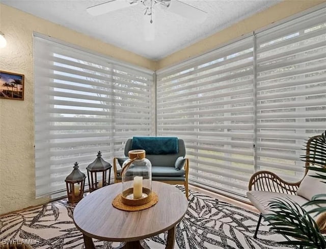 sitting room with a textured ceiling, a ceiling fan, and a textured wall