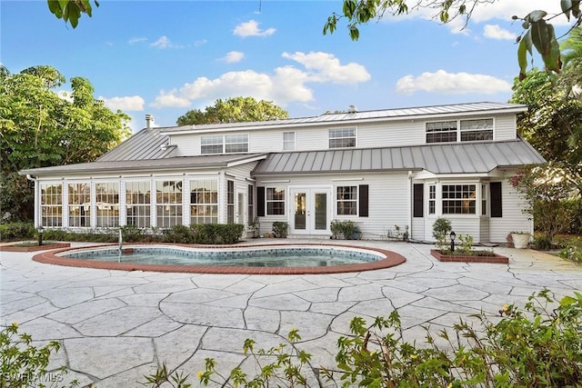 back of property featuring french doors, a sunroom, an outdoor pool, metal roof, and a patio area