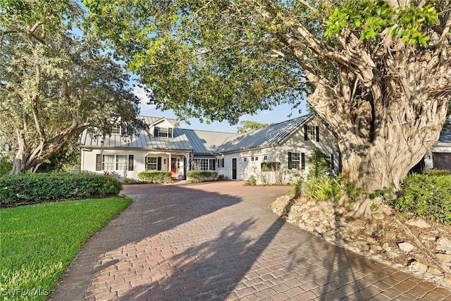 view of front of house featuring a standing seam roof, decorative driveway, an attached garage, and metal roof